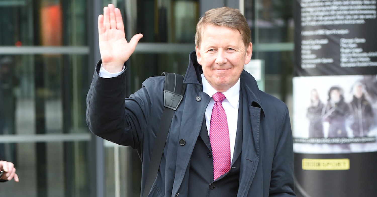 Bill Turnbull in a suit and red tie waving to cameras outside