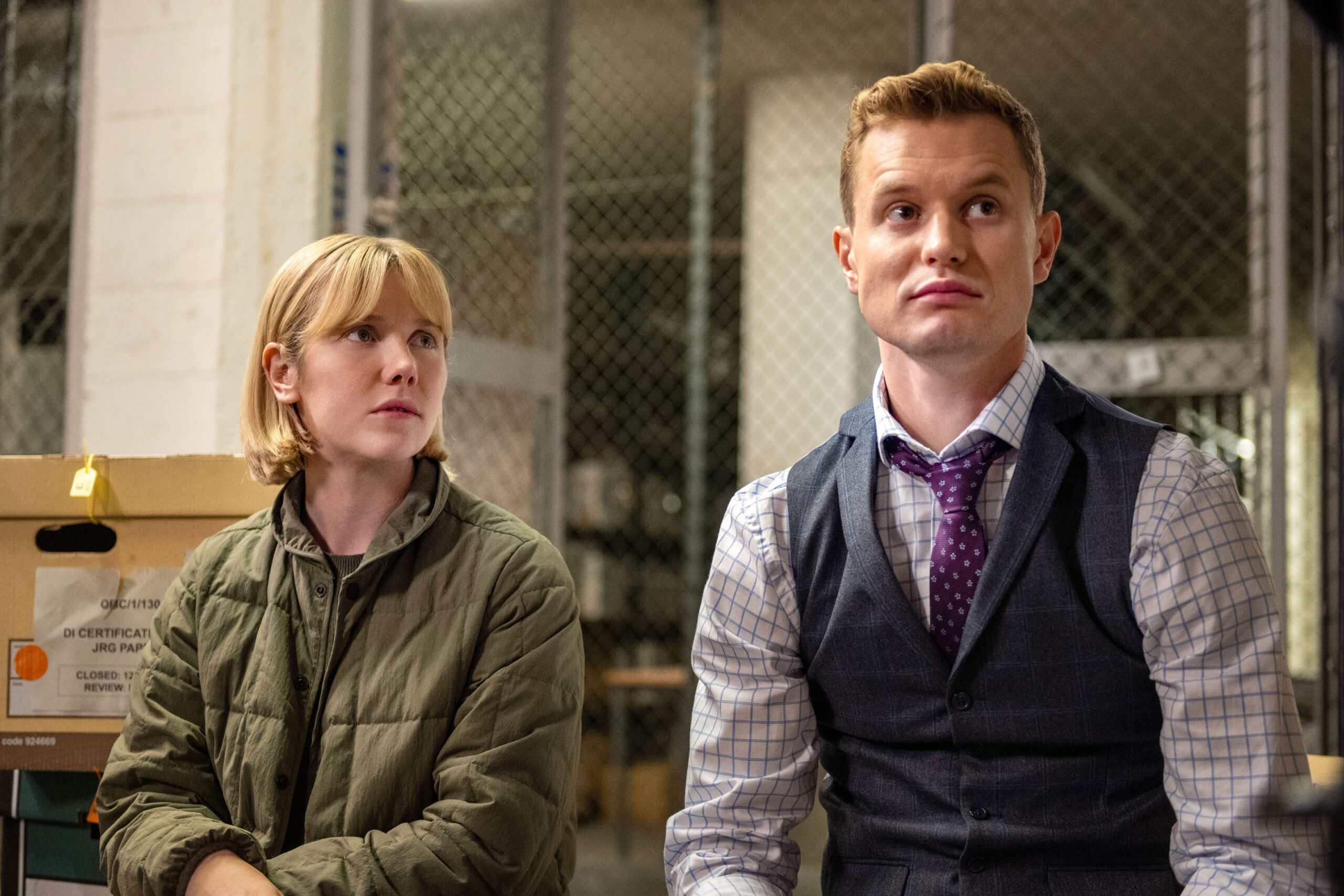 Lauren Lyle as Karen Pirie and Chris Jenks as DS Murray, they sit in a evidence locker as Karen looks up at Murray
