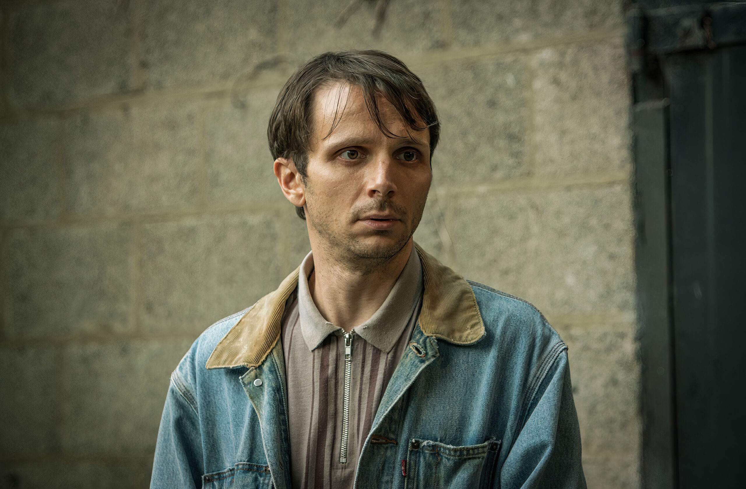 Mark Quartley as Edgar in Inside Man, he looks upset and he looks to his right in a denim jacket