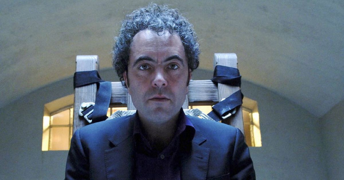 James Nesbitt as Tom in Steven Moffat show Jekylll, he sits on a chair, wearing all black with a pained expression