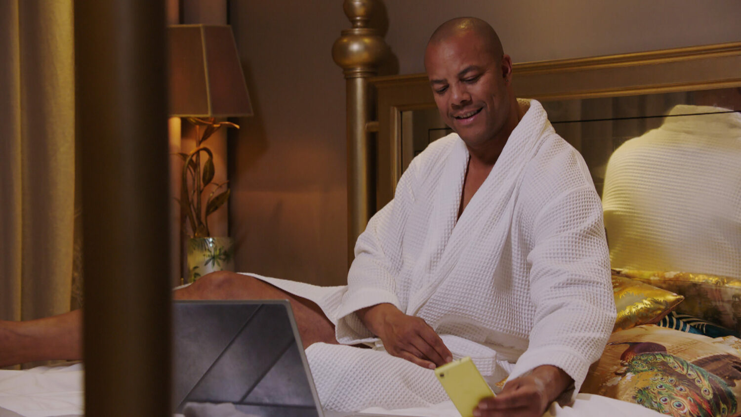 Emmerdale Al in bed looking at Chas's phone and smiling