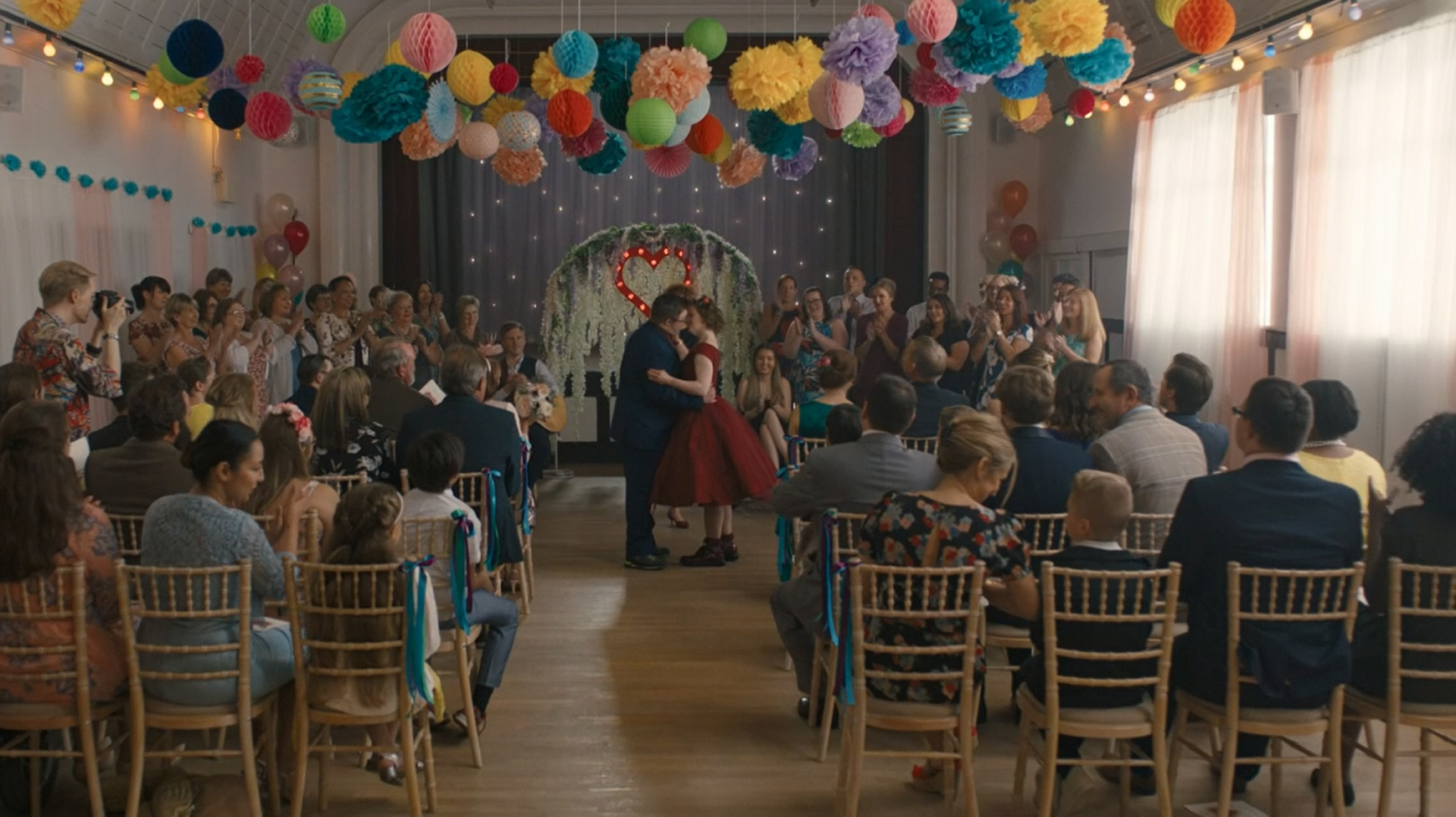 Ralph and Katie stand in the middle of their wedding ceremony, there are balloons all around