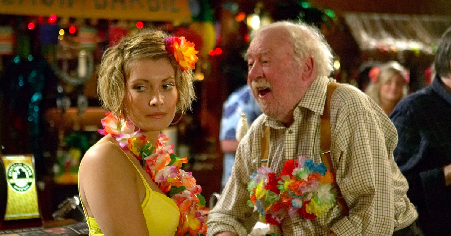 Older man flirting with an uninterested woman inside a pub 