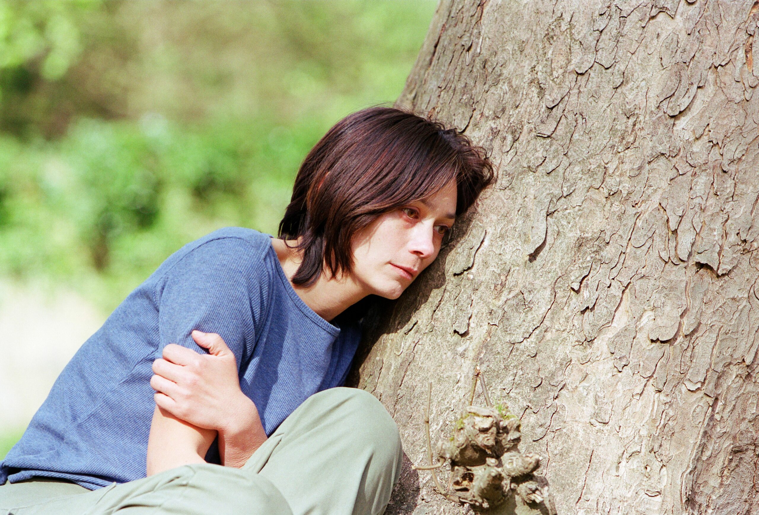 Zoe Tate huddles by a tree