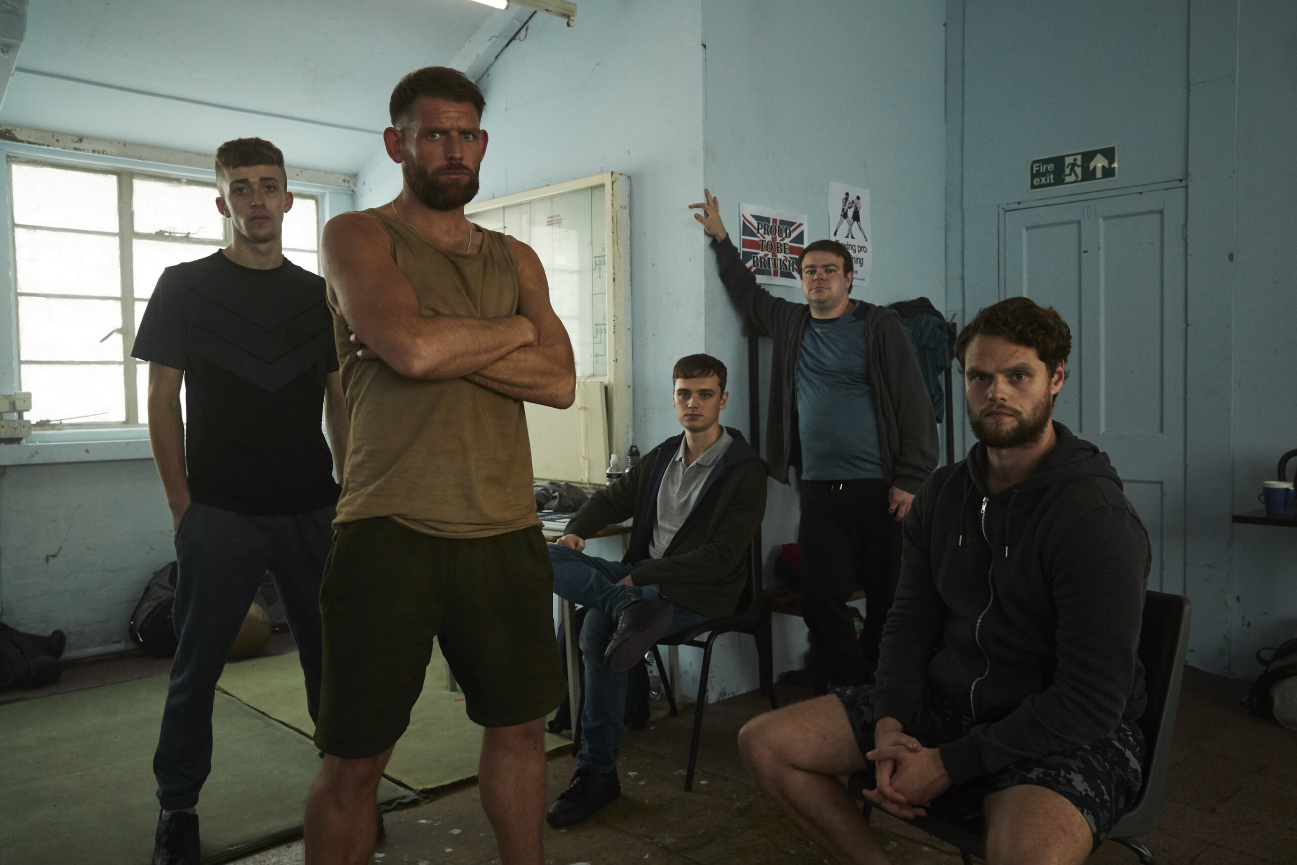 EZRA WATSON as Garron,CHRISTOPHER COGHILL as Chris,DEAN-CHARLES CHAPMAN as Jack,ANDREW ELLIS as Robbie and BOBBY SCHOFIELD as Matt in The Walk-In. They stand in a group, they all have frowns and look threatening