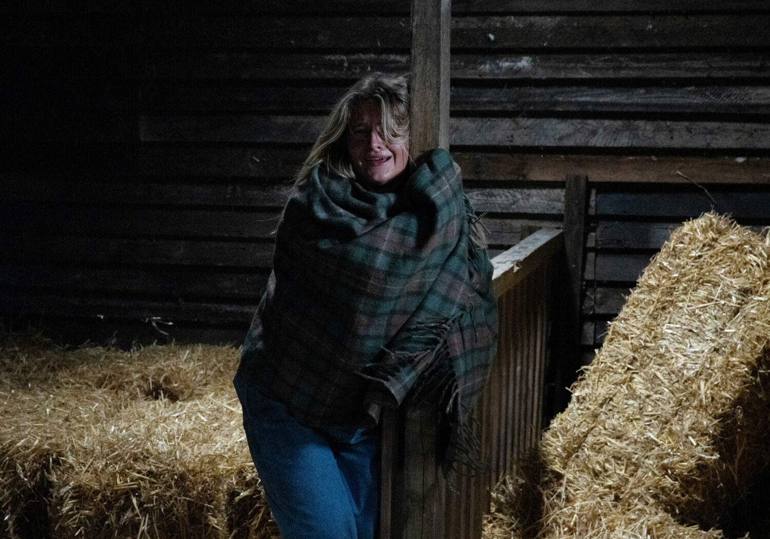 Emmerdale Amelia wrapped in a blanket, holding onto a post, crying