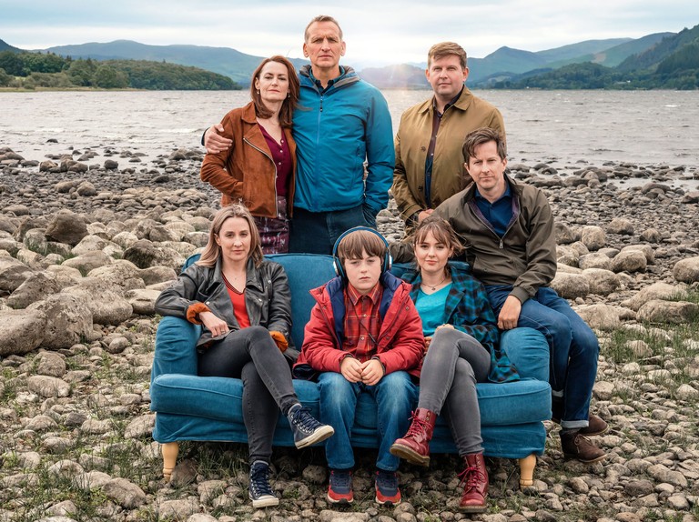 The cast of The A Word sit together on a sofa on a beach in the lakes in series 3