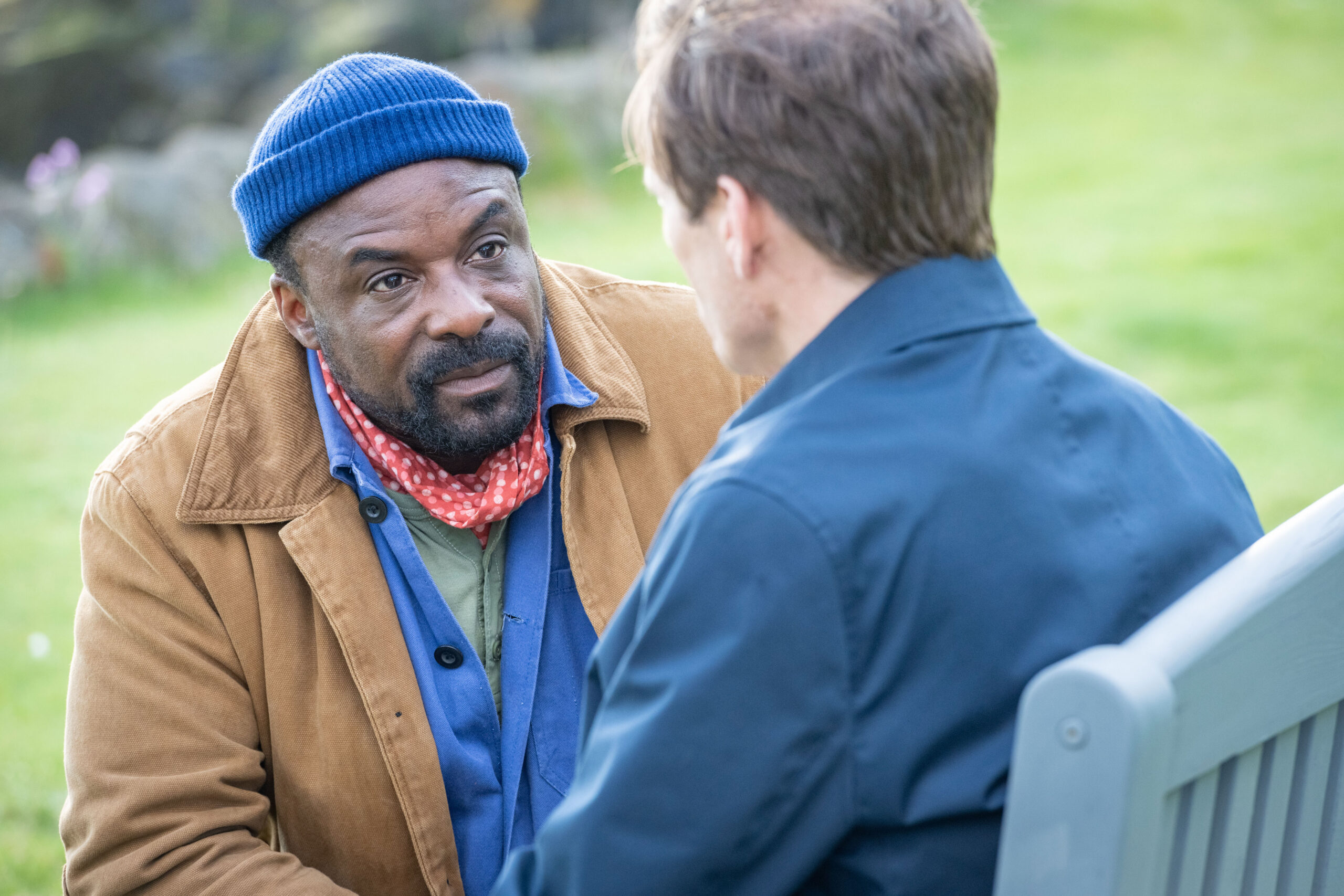 Ariyon Bakare as Alex and Michael Schaeffer as Weird in Karen Pirie, they sit on a park bench with worried faces