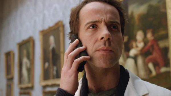 Jonjo O'Neill as McGillop in Doctor Who, he holds his phone to his ear with an angry face in a gallery