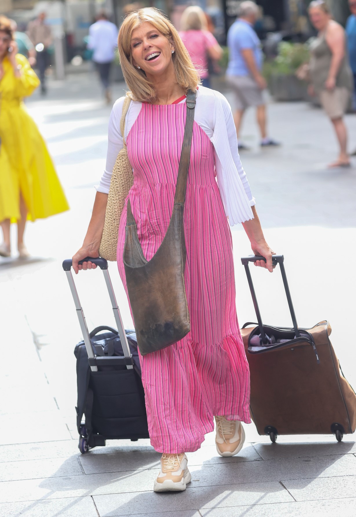 Kate Garraway in pink outfit pulling a suitcase