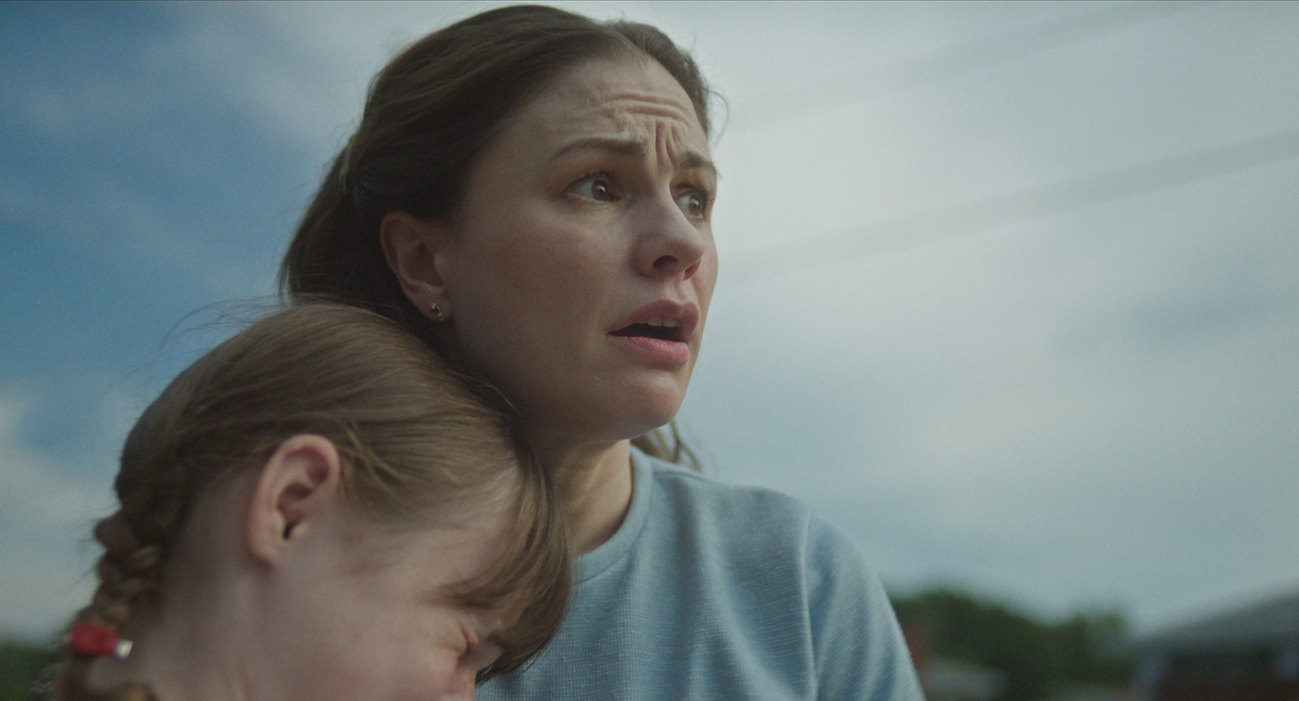 Anna Paquin as Mary Ann Broberg in A Friend of the Family, she holds a child and gasps and looks up at the sky