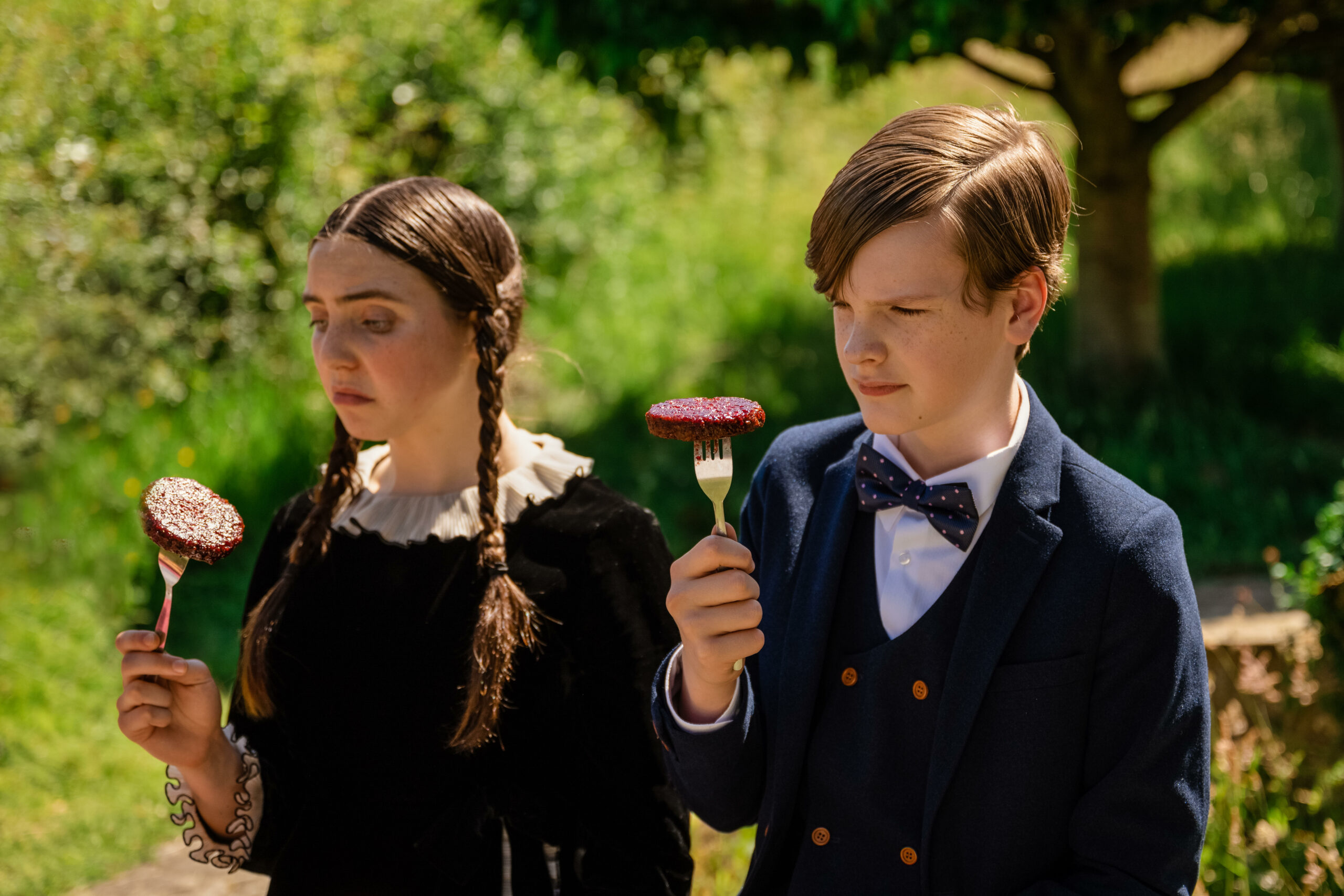 Hector Bateman and Lucy Allix eating meat on a fork in The Larkins