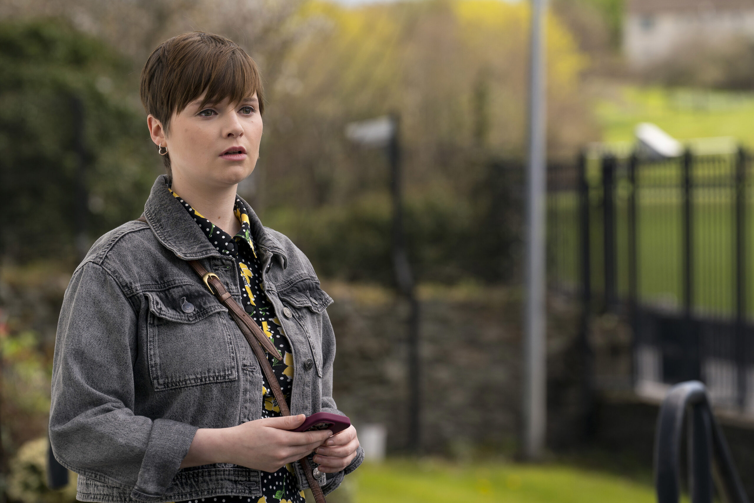 Bloodlands episode 5: Lola Petticrew as Izzy Brannick, she holds her phone and looks upset as she stands outside