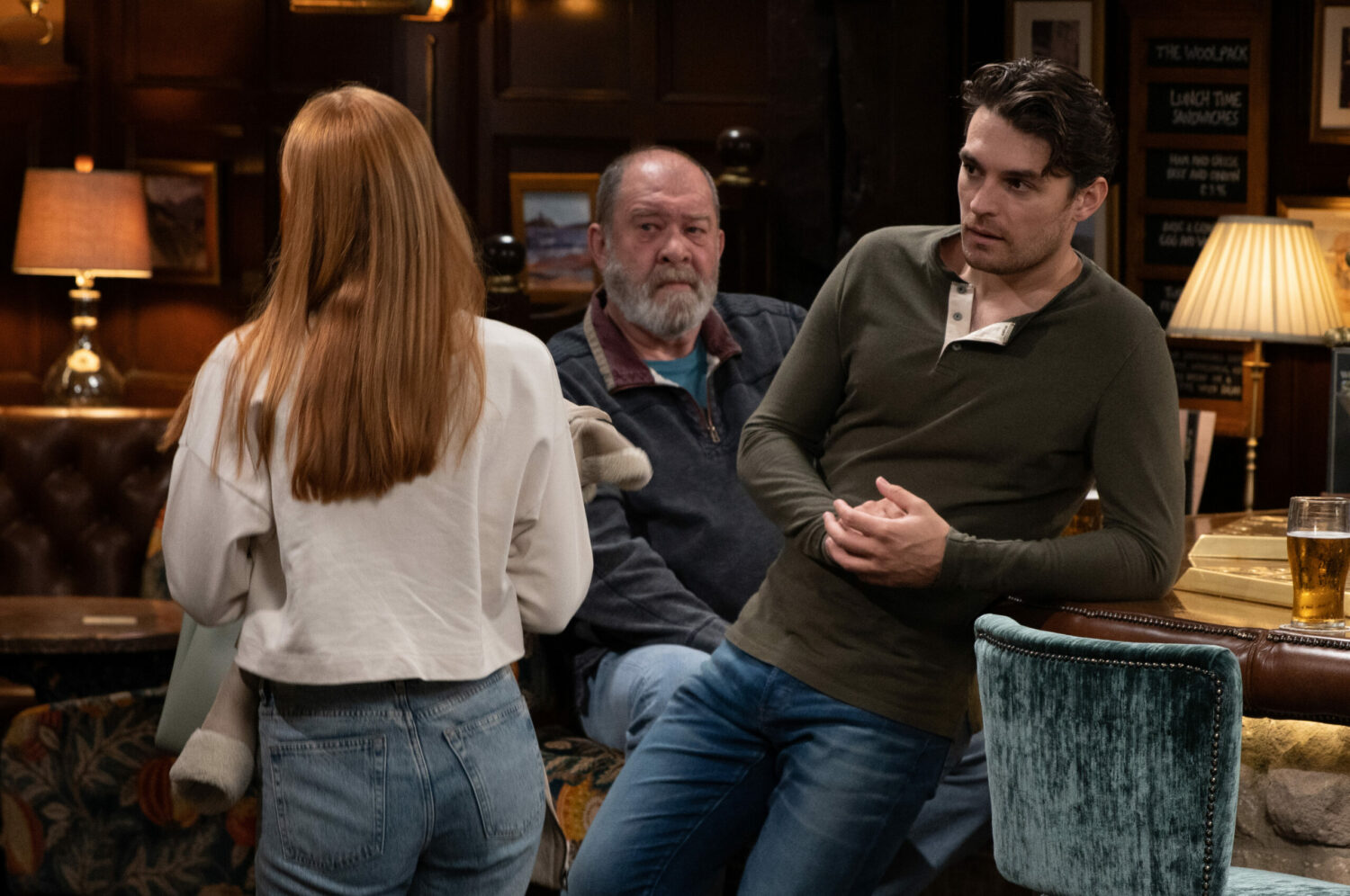 Mackenzie learning against the bar as Chloe walks by emMERDALE