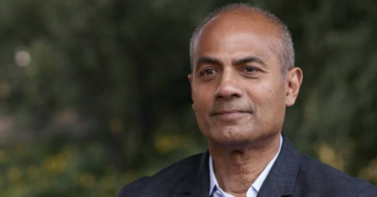 George Alagiah listens as he faces a camera