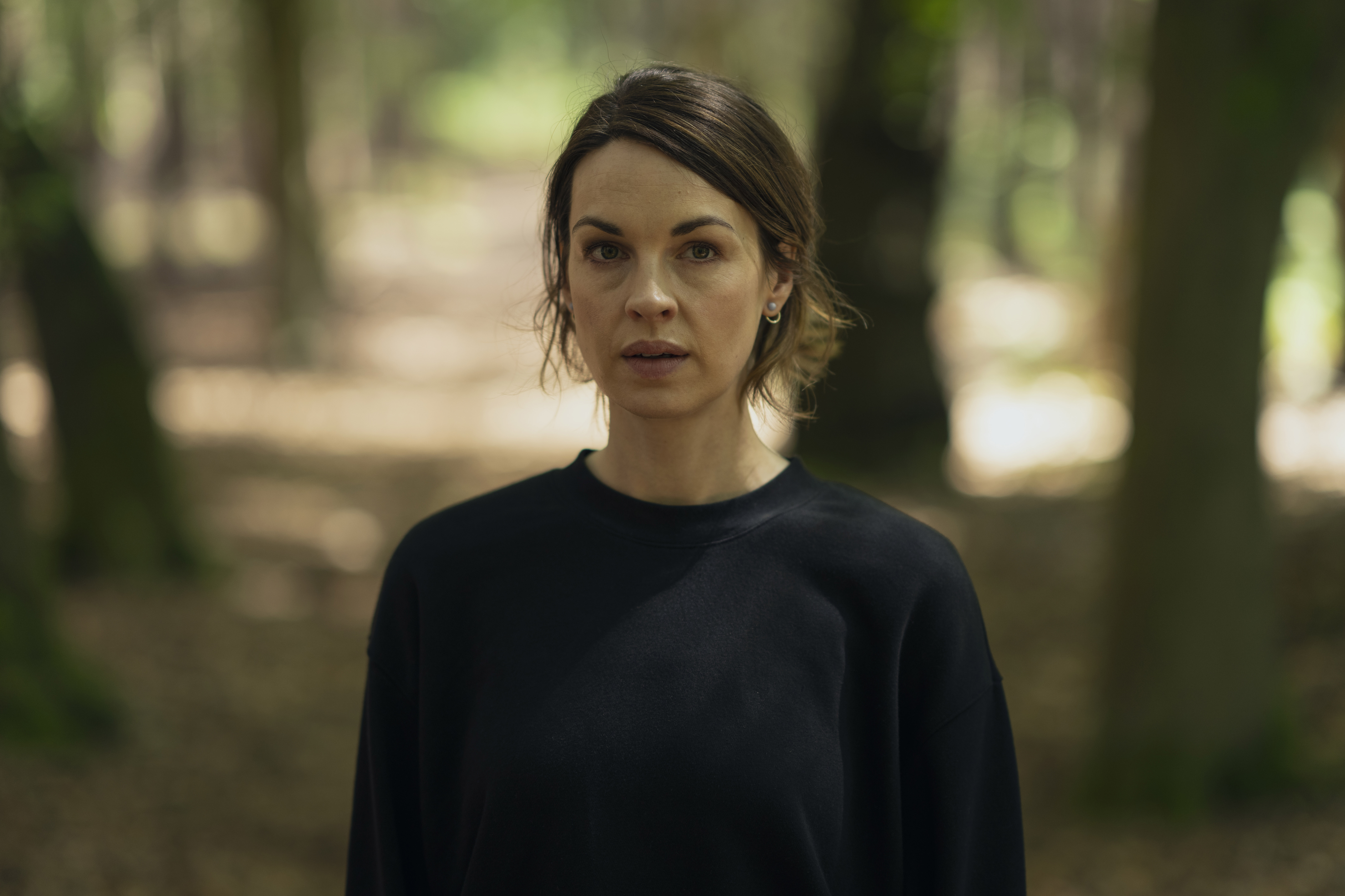 Jessica Raine as Lucy Chambers in The Devil's Hour in woods looking confused