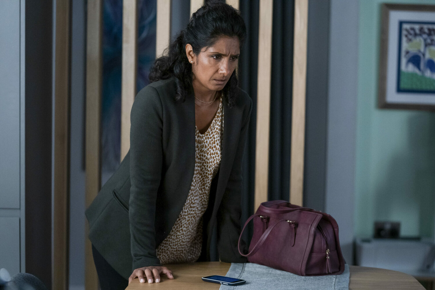 EastEnders Suki leaning over a table, worried