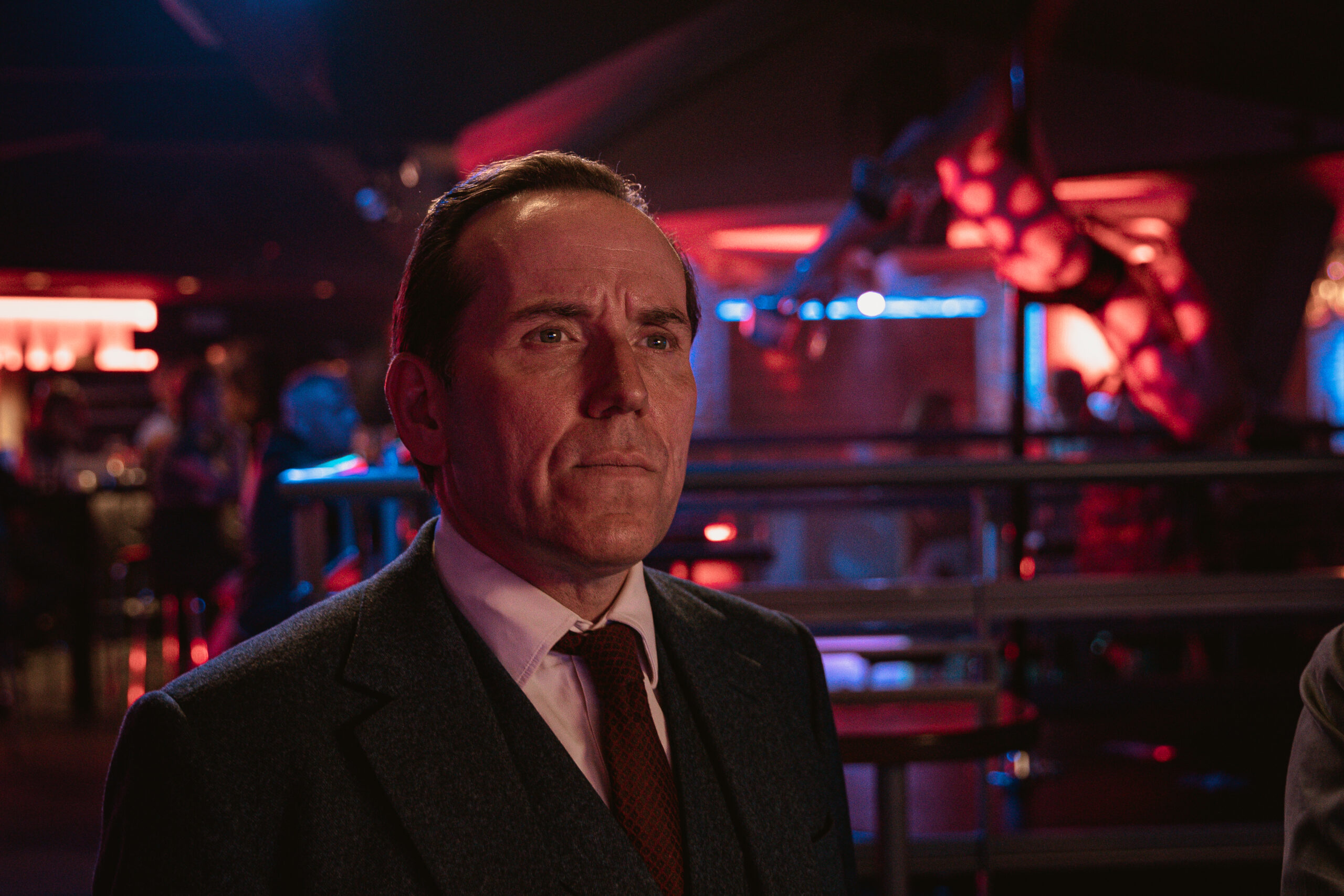 Ben Miller as Professor Jasper TEMPEST in Professor T, he looks up in a bar with a frown and a suit on
