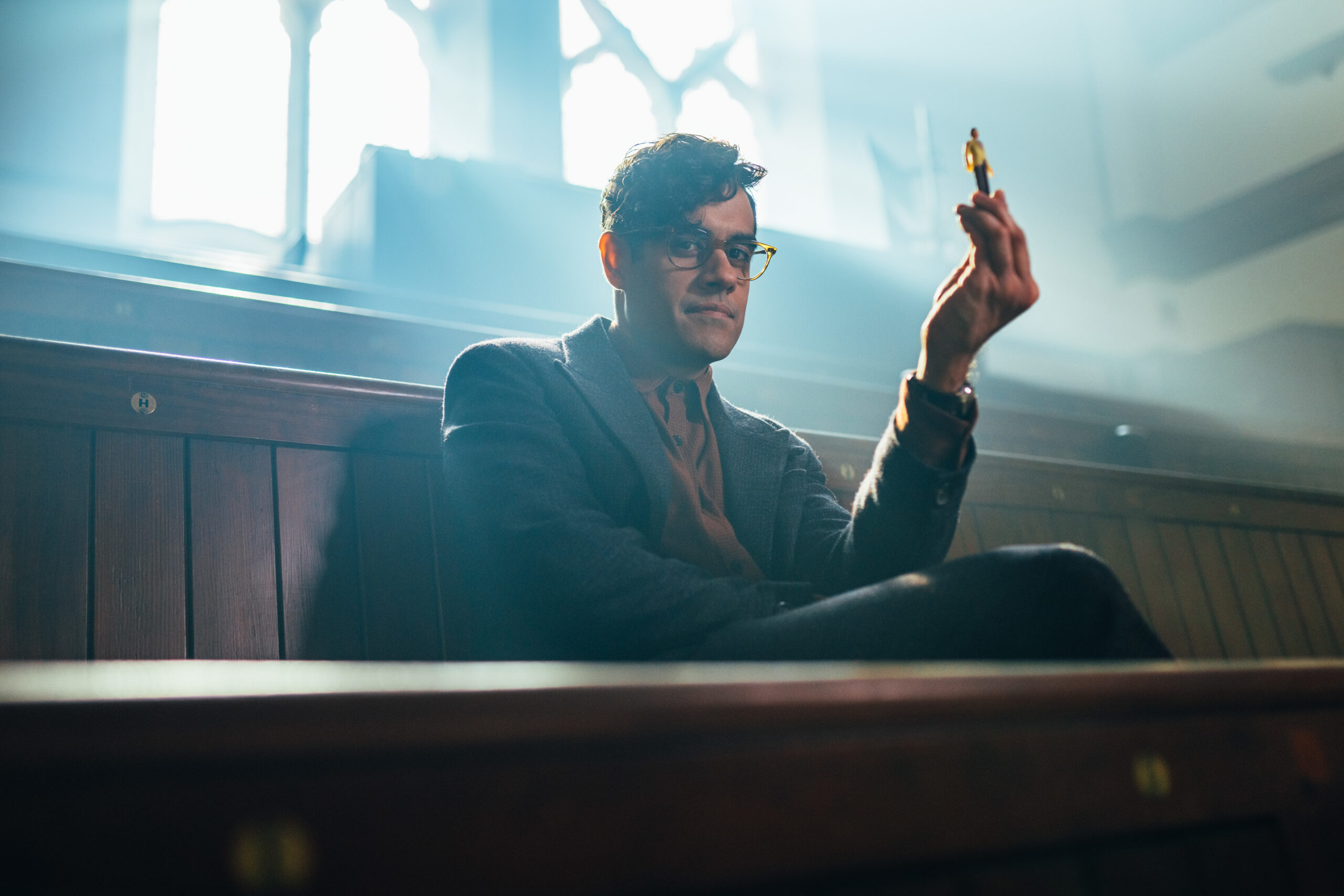 Sacha Dhawan as the master in doctor who, he holds up a small figure with a small smile