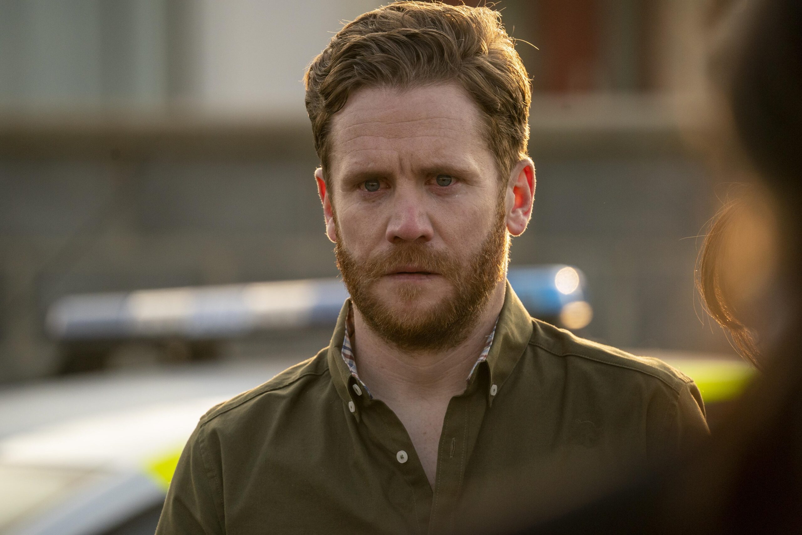 Ian Lloyd Anderson as OWEN in The House Across the Street, he stands in the street looking upset with a police car behind him