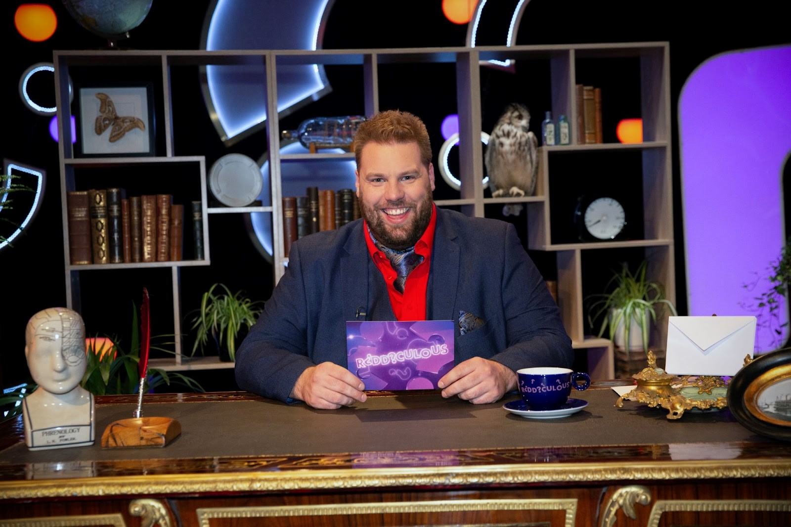 Henry Lewis smiling on set of ITV game show, Riddiculous