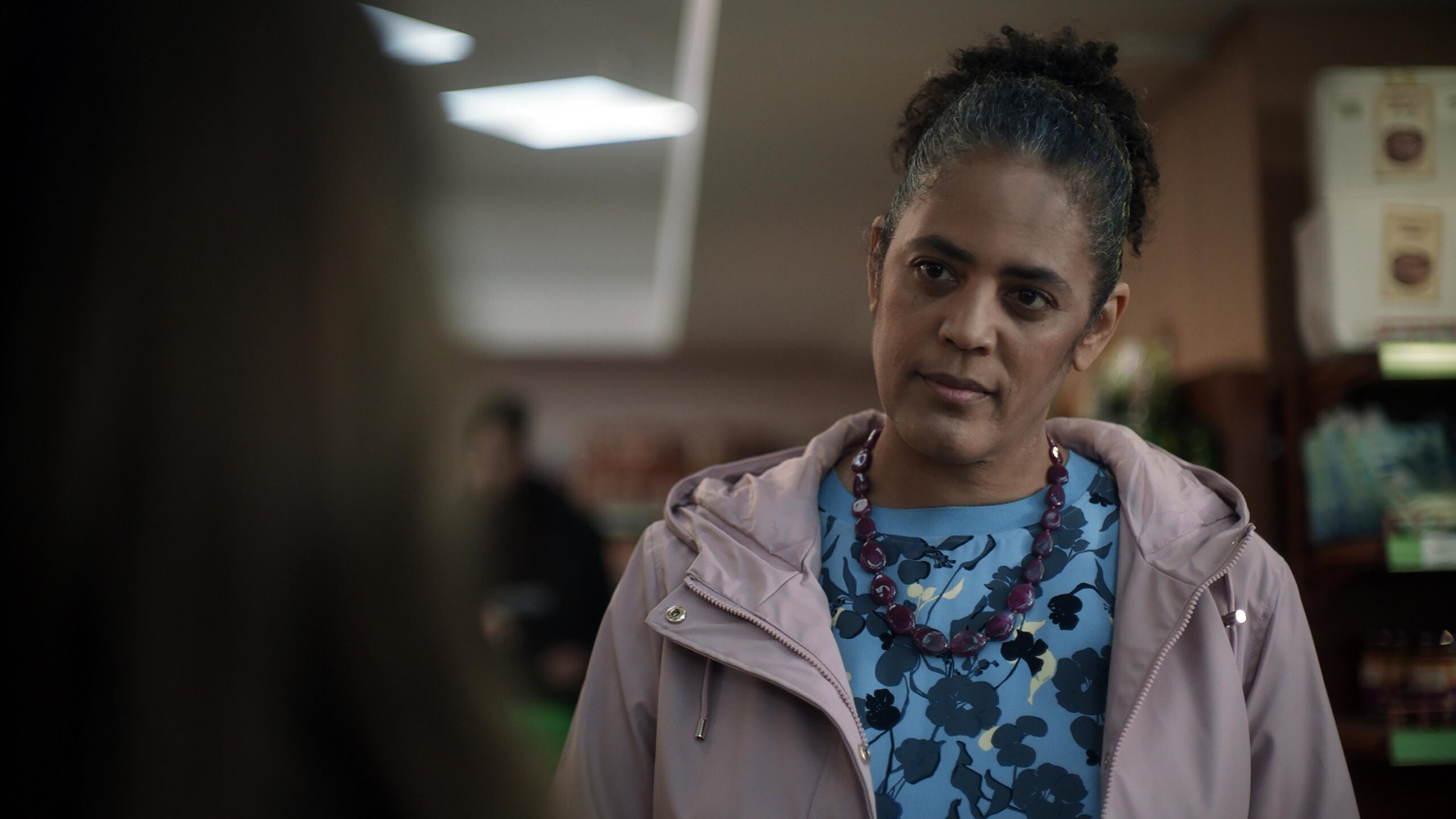 Sara Powell as Joanne in the house across the street, she looks down at Claudia with a frown in a supermarket