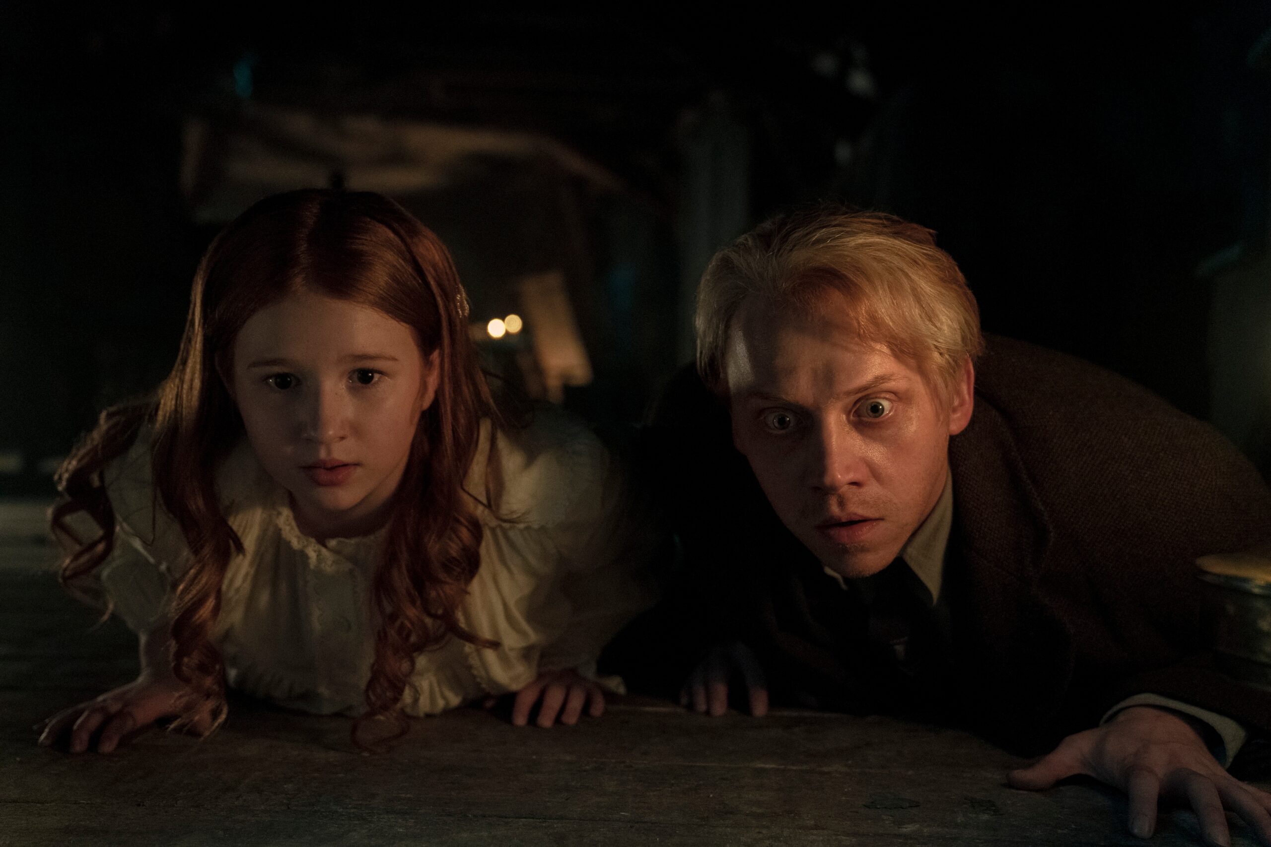 Rupert Grint and Daphne Hoskins are crawling along the floor anxiously in Cabinet of Curiosities on Netflix