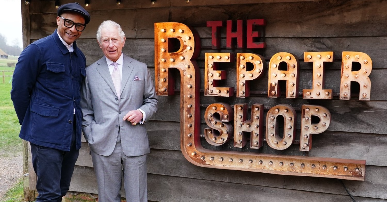 King Charles and Jay Blades posing with The Repair Shop logo beside them