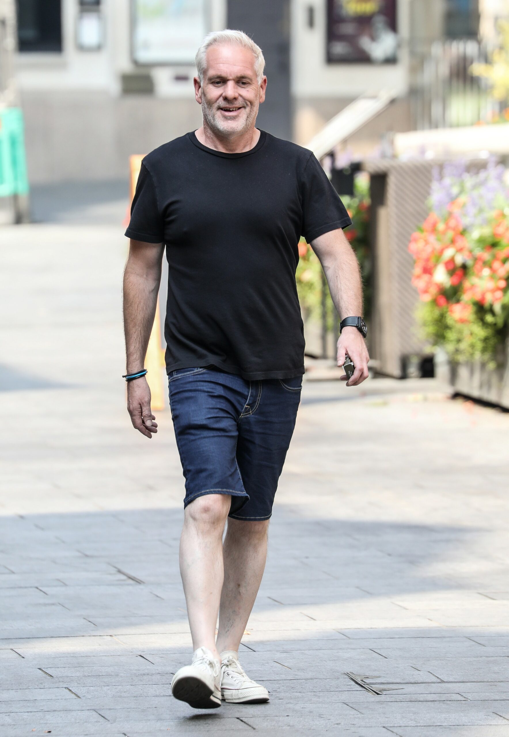Chris Moyles smiles at cameras outside radio studio