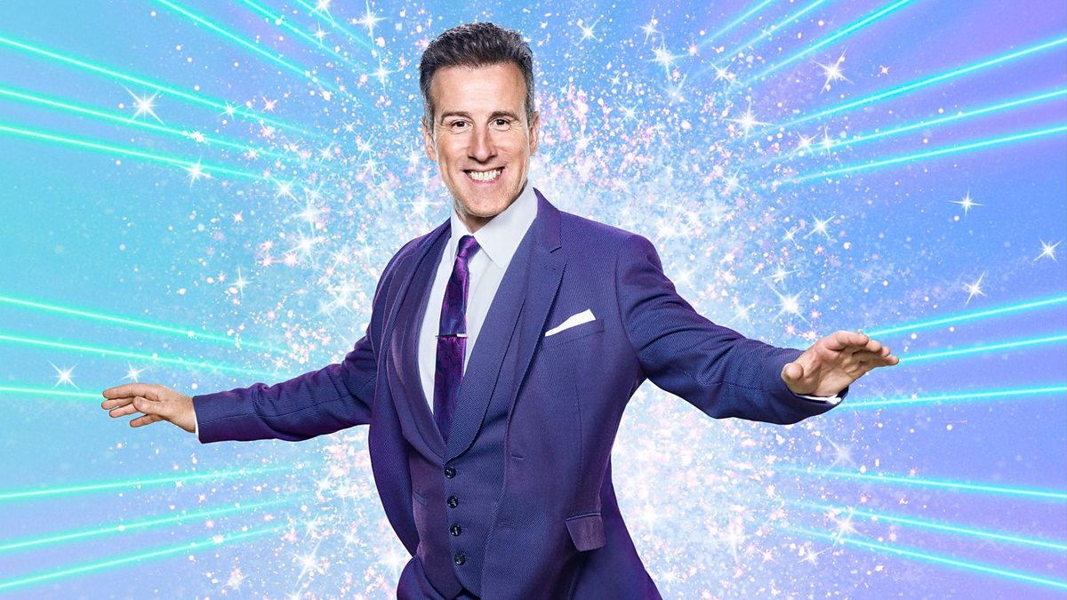 Anton Du Beke twirling around in front of a blue glitter board on Strictly