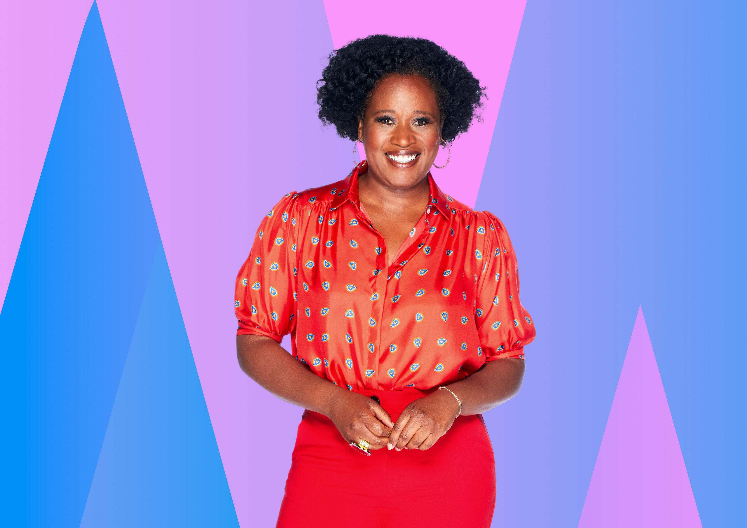 Charlene White smiling in an orange top and red skirt