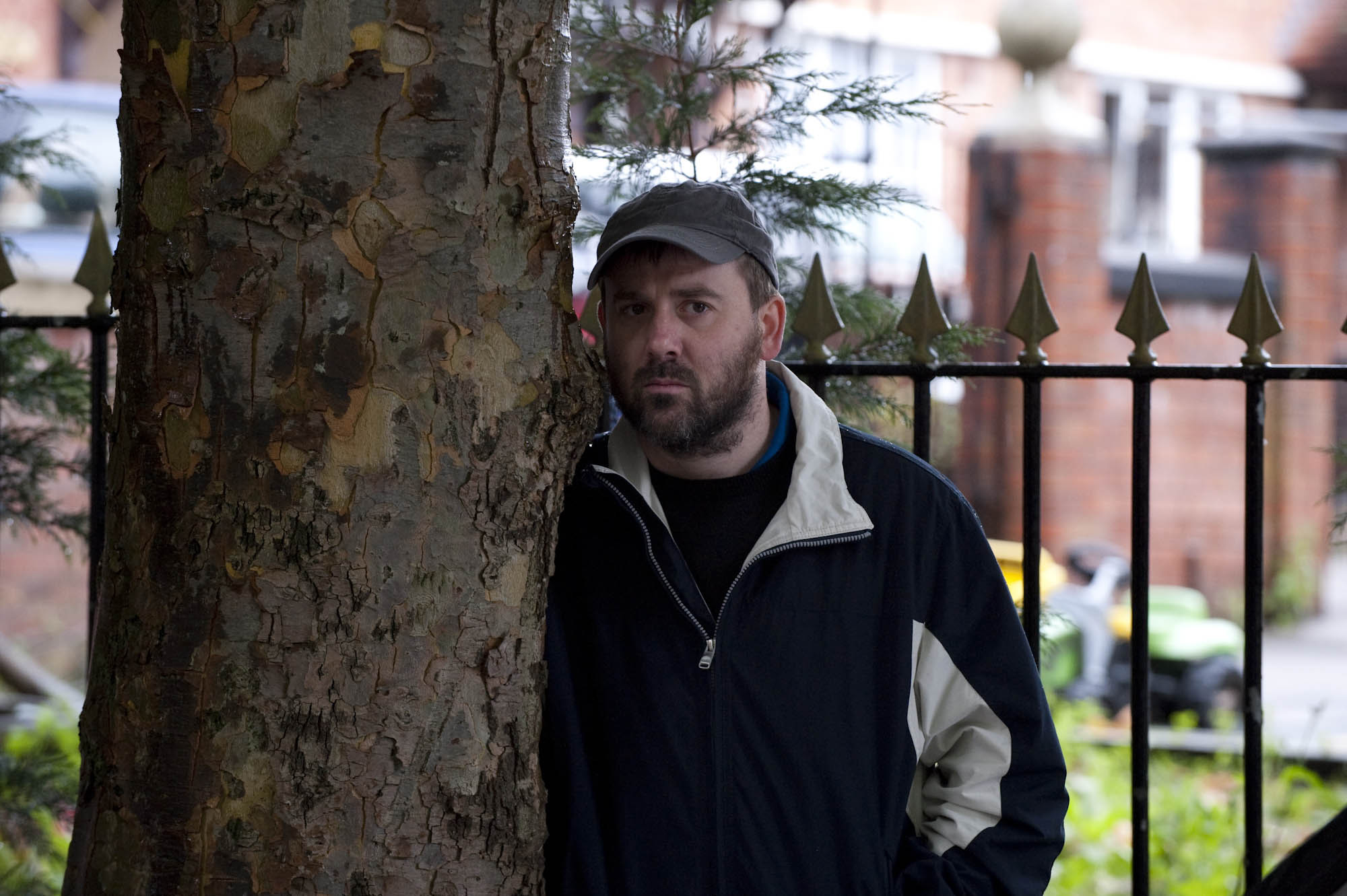 John Stape looking suspicious stood by a tree in Coronation Street