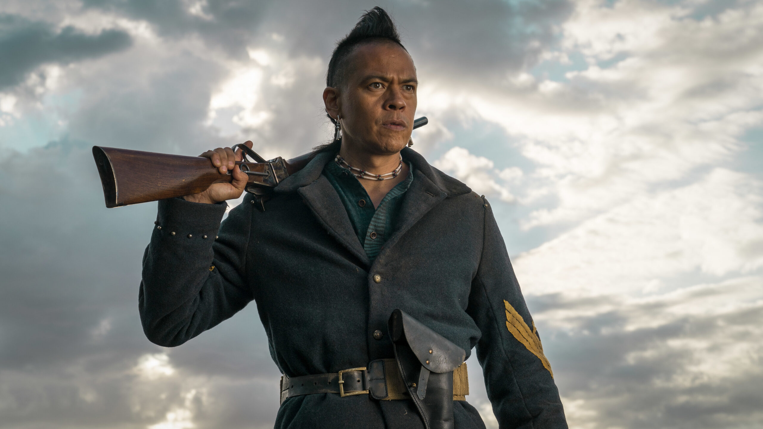 Eli holds his gun over his back in The English