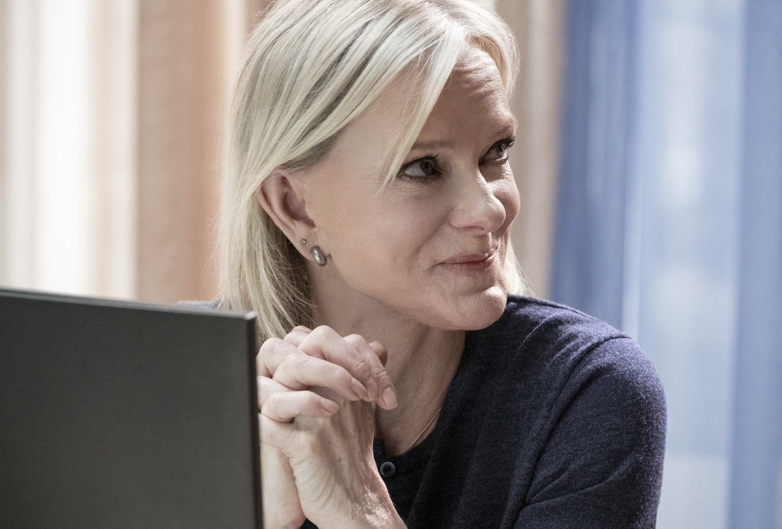 Maureen smiles with her hands together in Riches