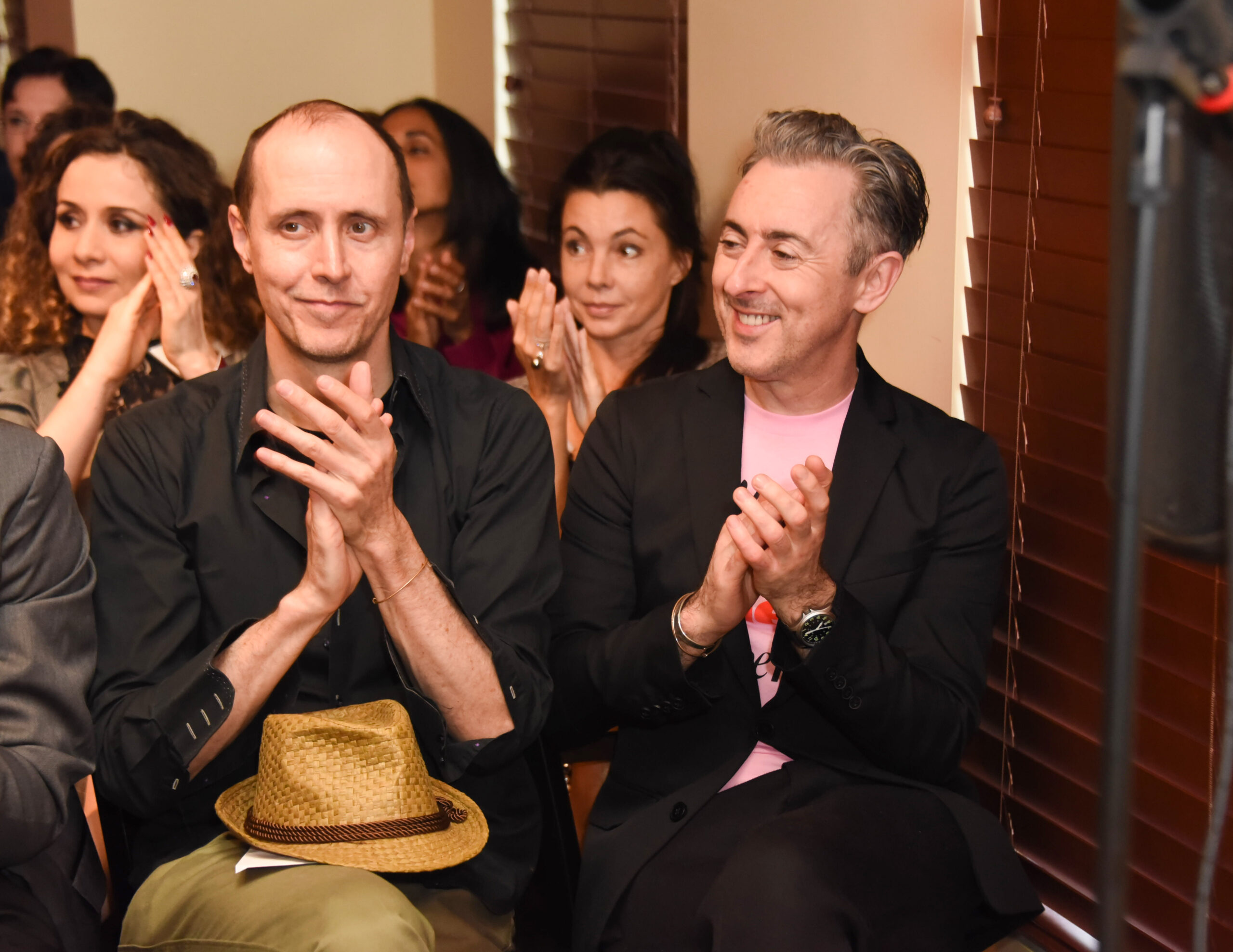 Alan Cumming and husband Grant Shaffer clap at event