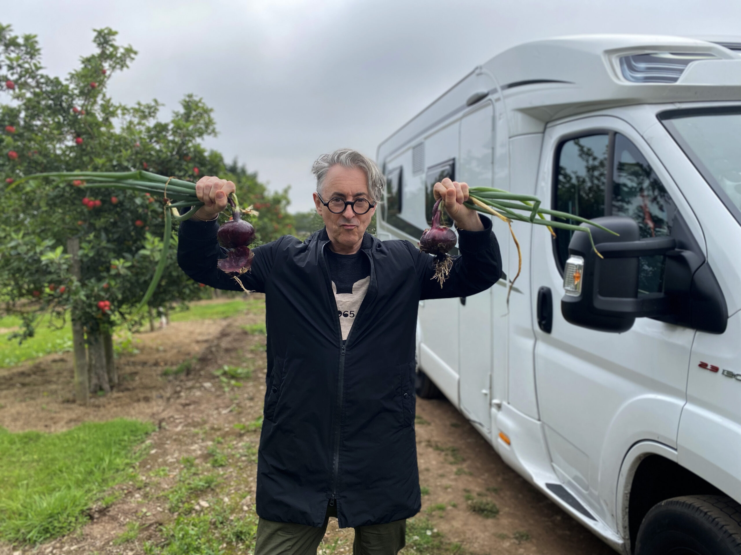 Alan Cumming holds up vegetables in Lost in Scotland and Beyond