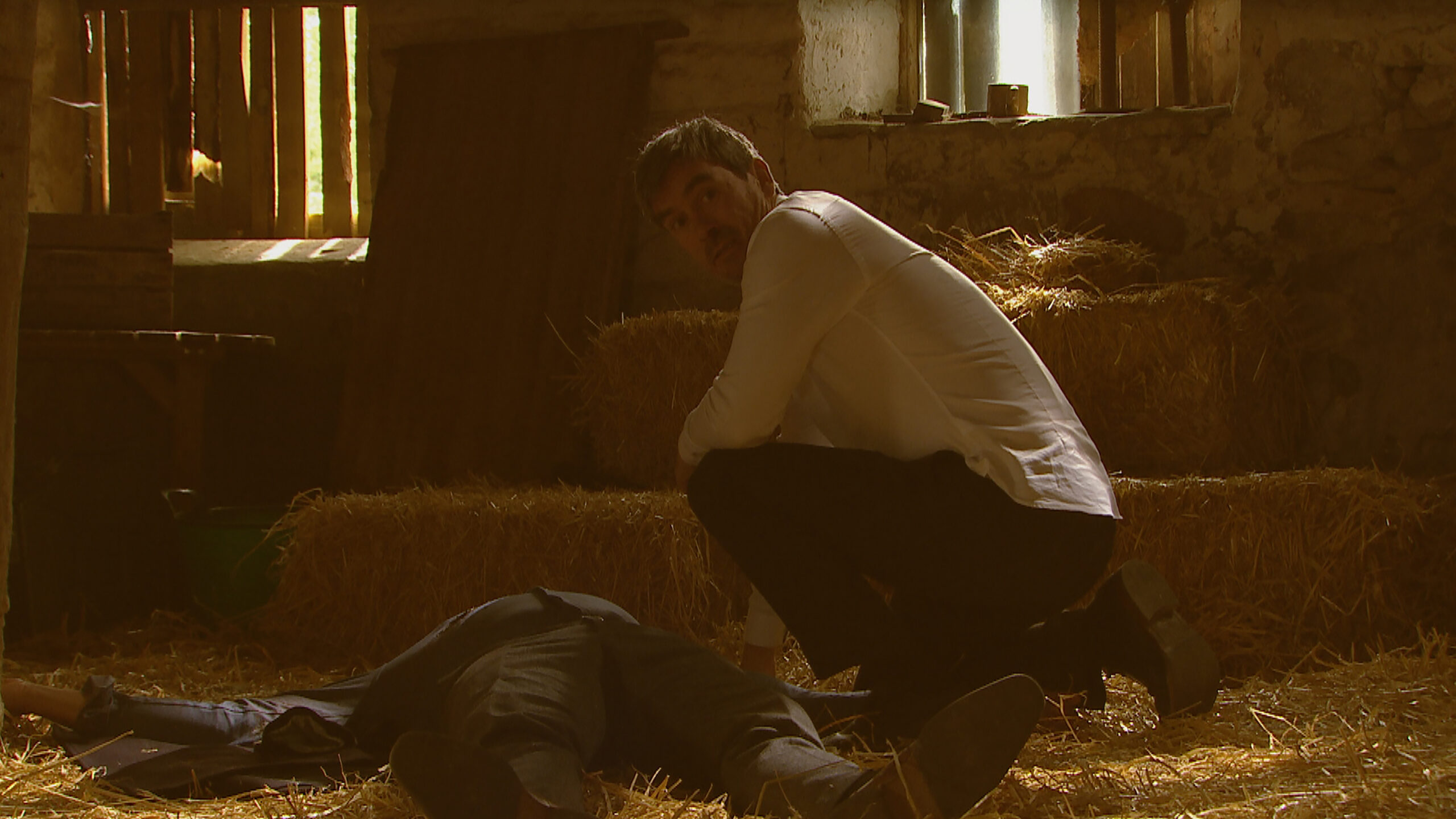 Cain looks at Kyle shocked as he stands over Al's dead body in Emmerdale 
