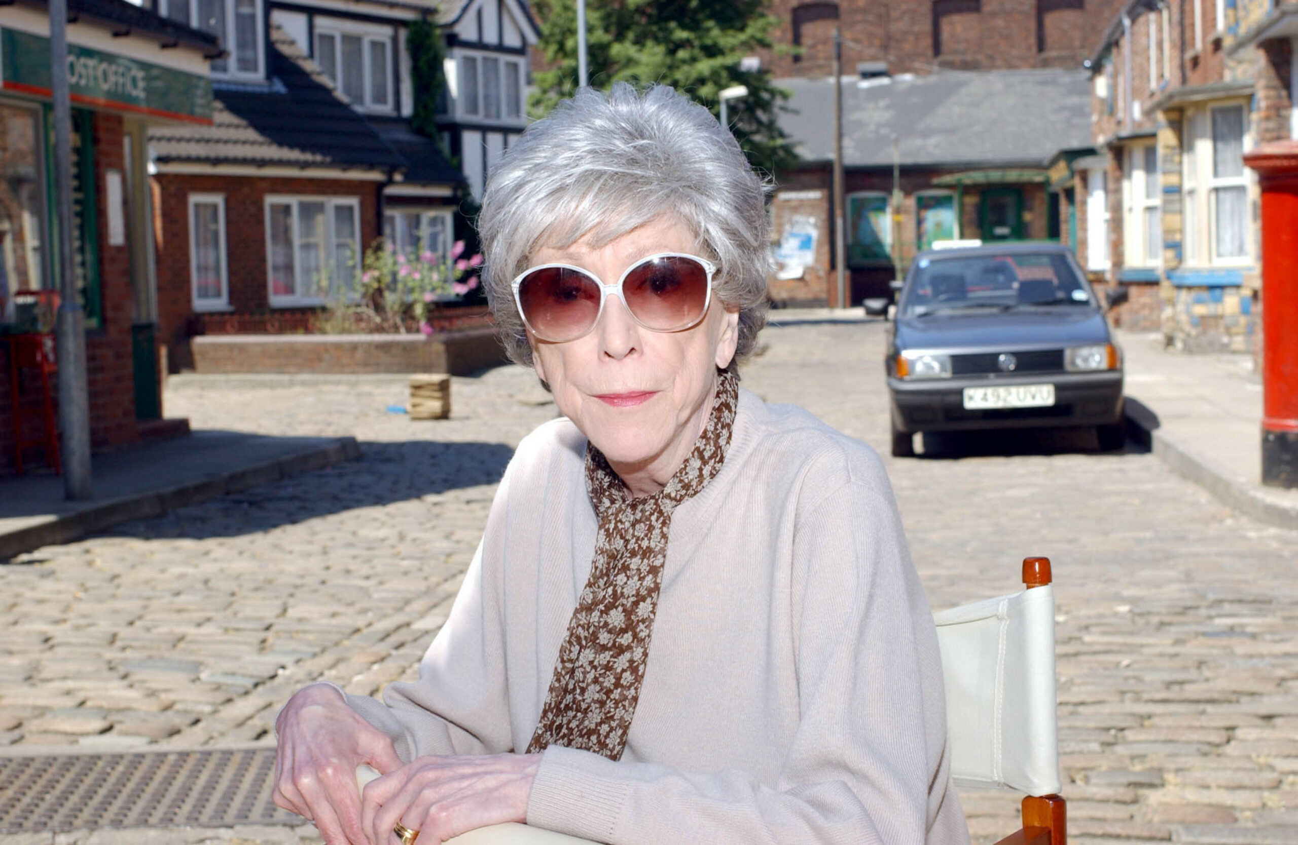 Blanche sitting outside wearing sunglasses on Coronation Street