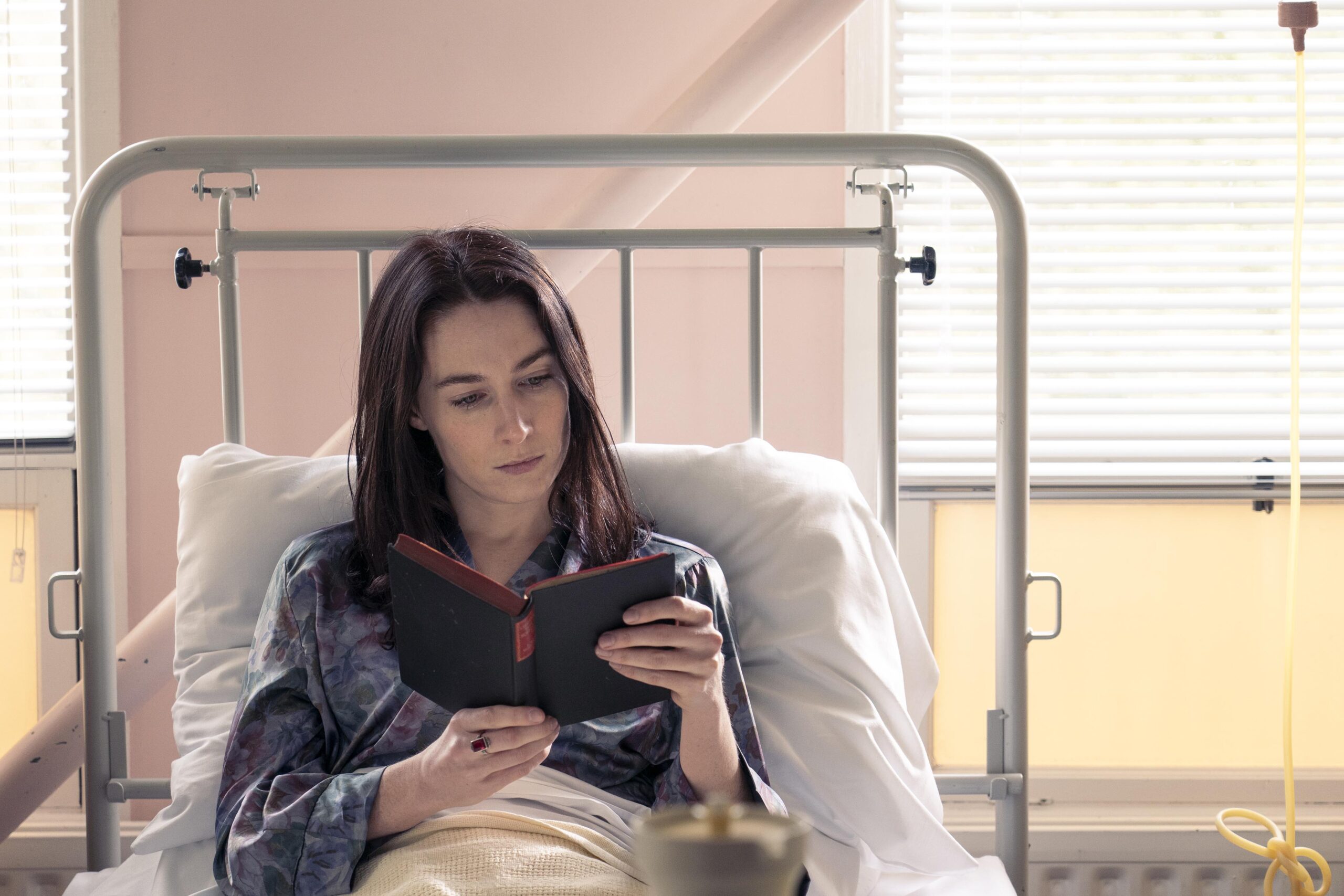 Josephine sits and reads a book in a bed