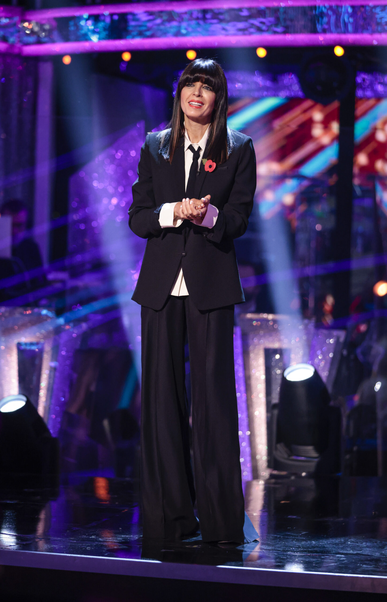 Claudia Winkleman in black suit and white shirt hosting Strictly