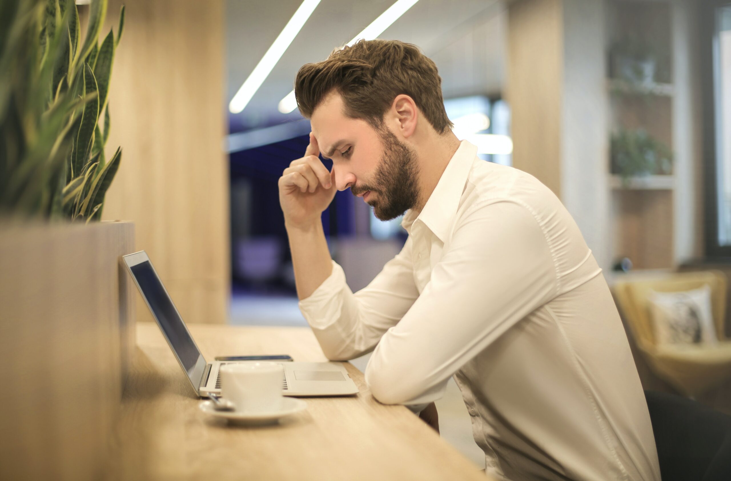 A man looking stressed sat at his laptop