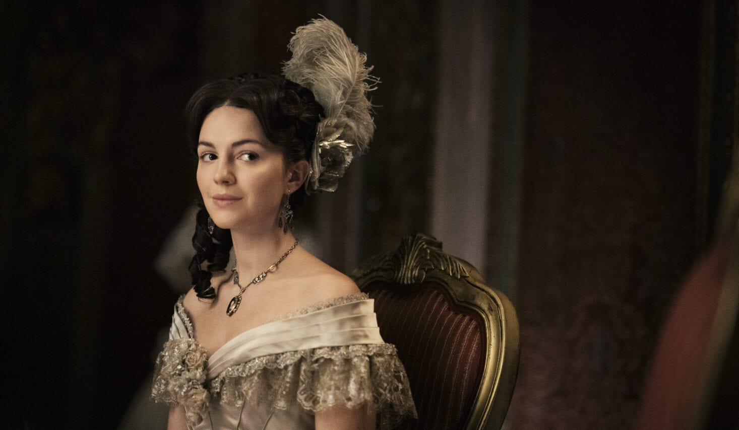 Sue Gilbert smiles on a chair in Dickinson