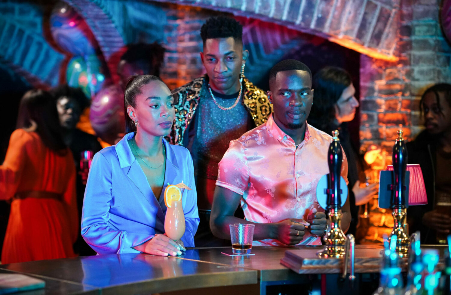 Finlay and Felix stand by Chelsea at the bar 