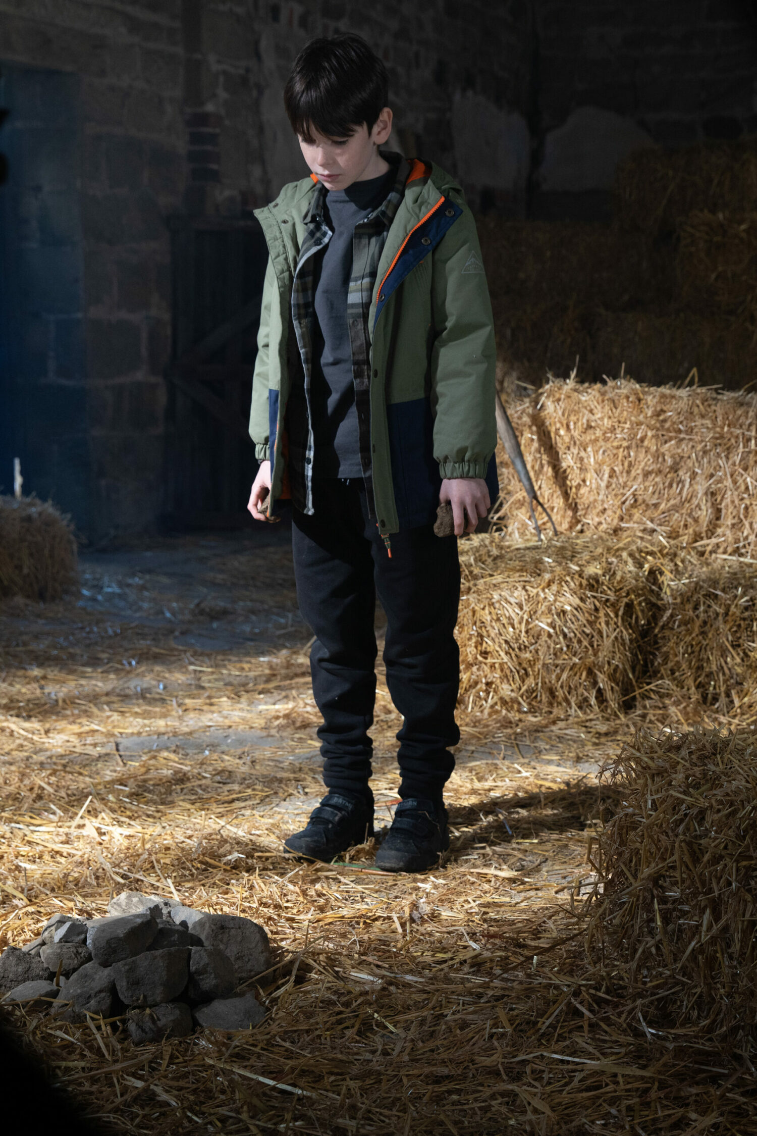Kyle stands over a pile of rocks in the barn