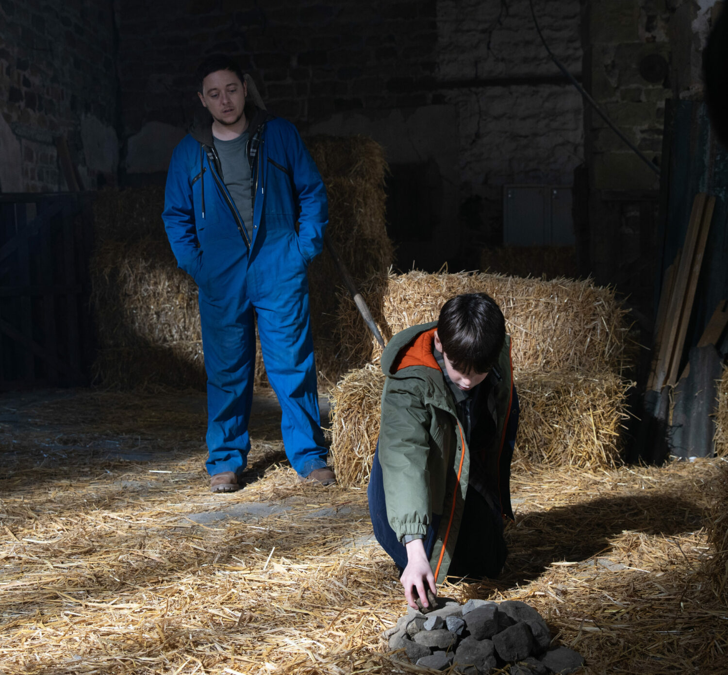 Emmerdale's Matty is watching Kyle form a pile of rocks, in the barn