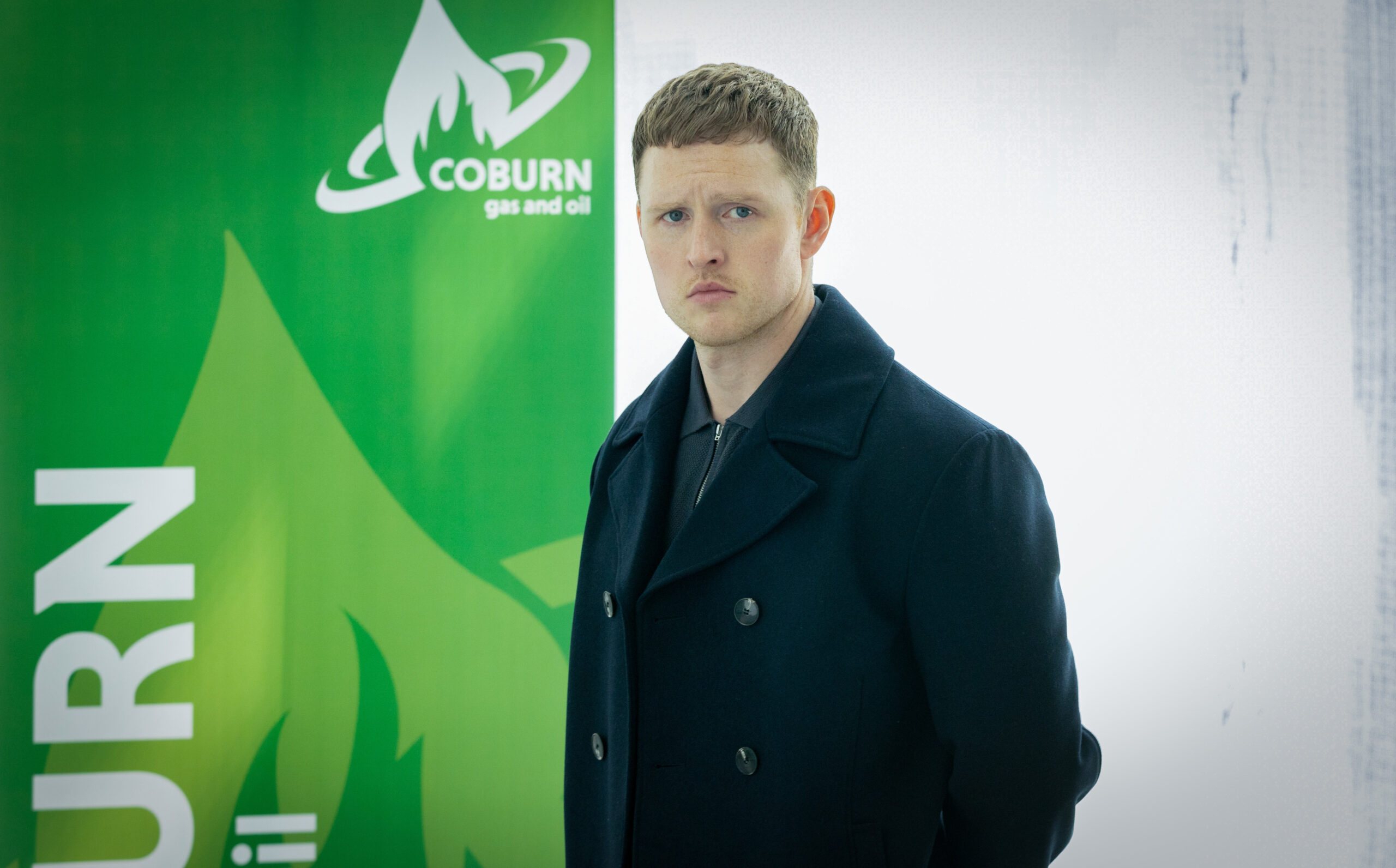 Ewan Macclure stands next to a Coburn poster in Granite Harbour