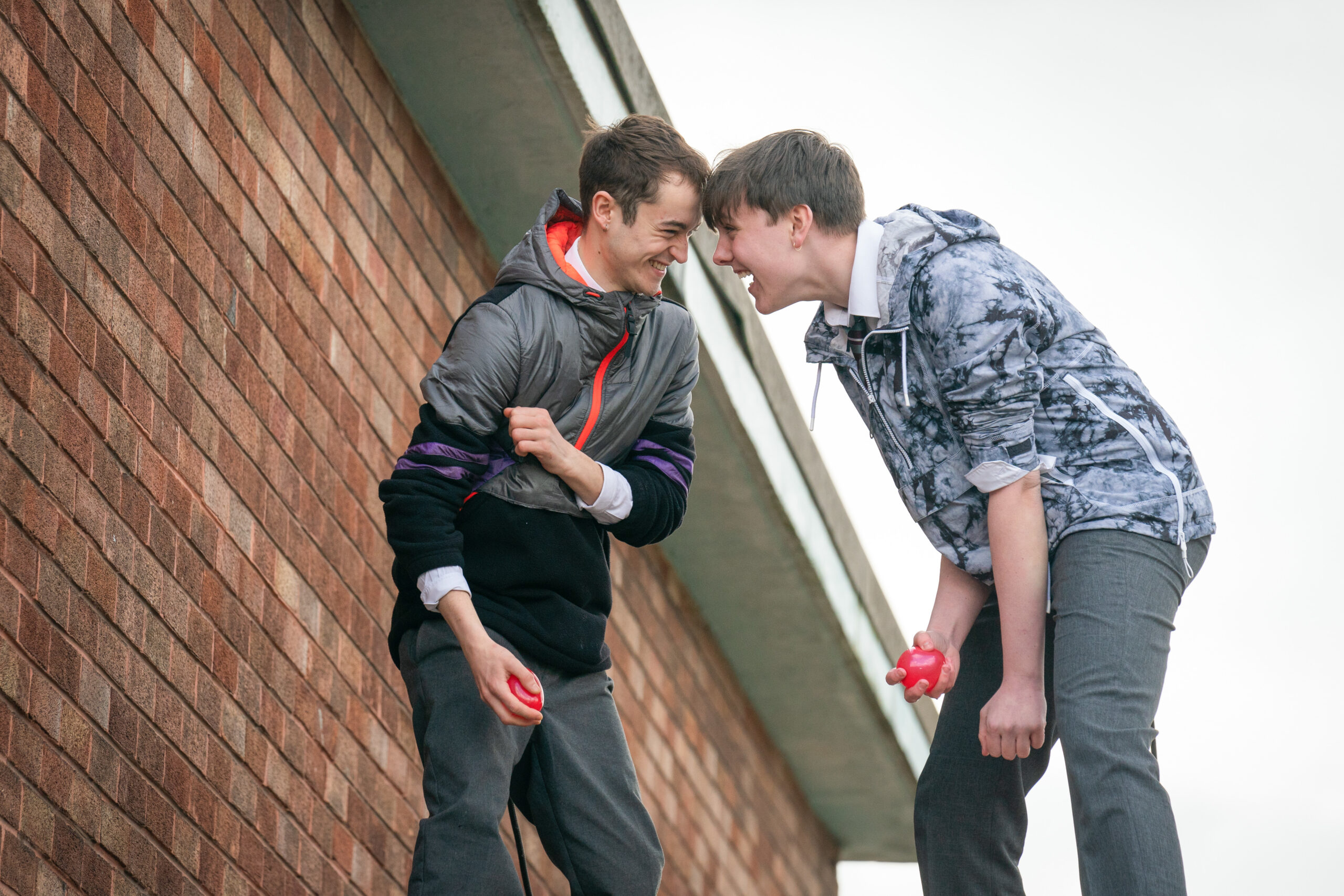 Two pupils smile at each other as they hold Water balloons in Waterloo Road 