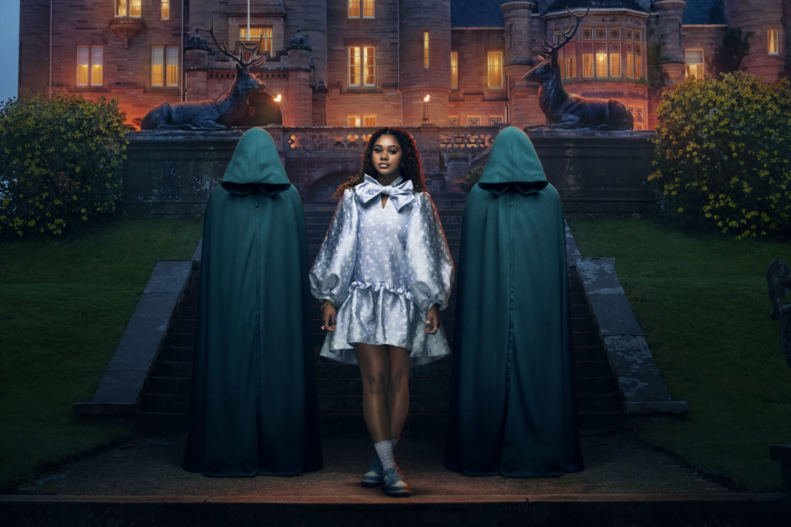 Contestant Aisha poses with the two hoods on the Traitors