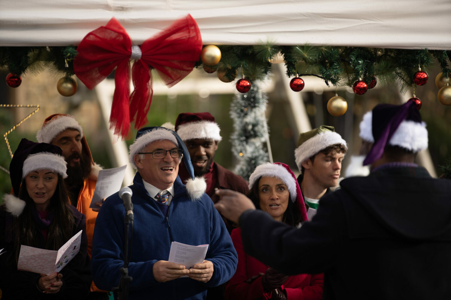 Emmerdale's Bob and Manpreet and singing in the choir whilst wearing Santa hats