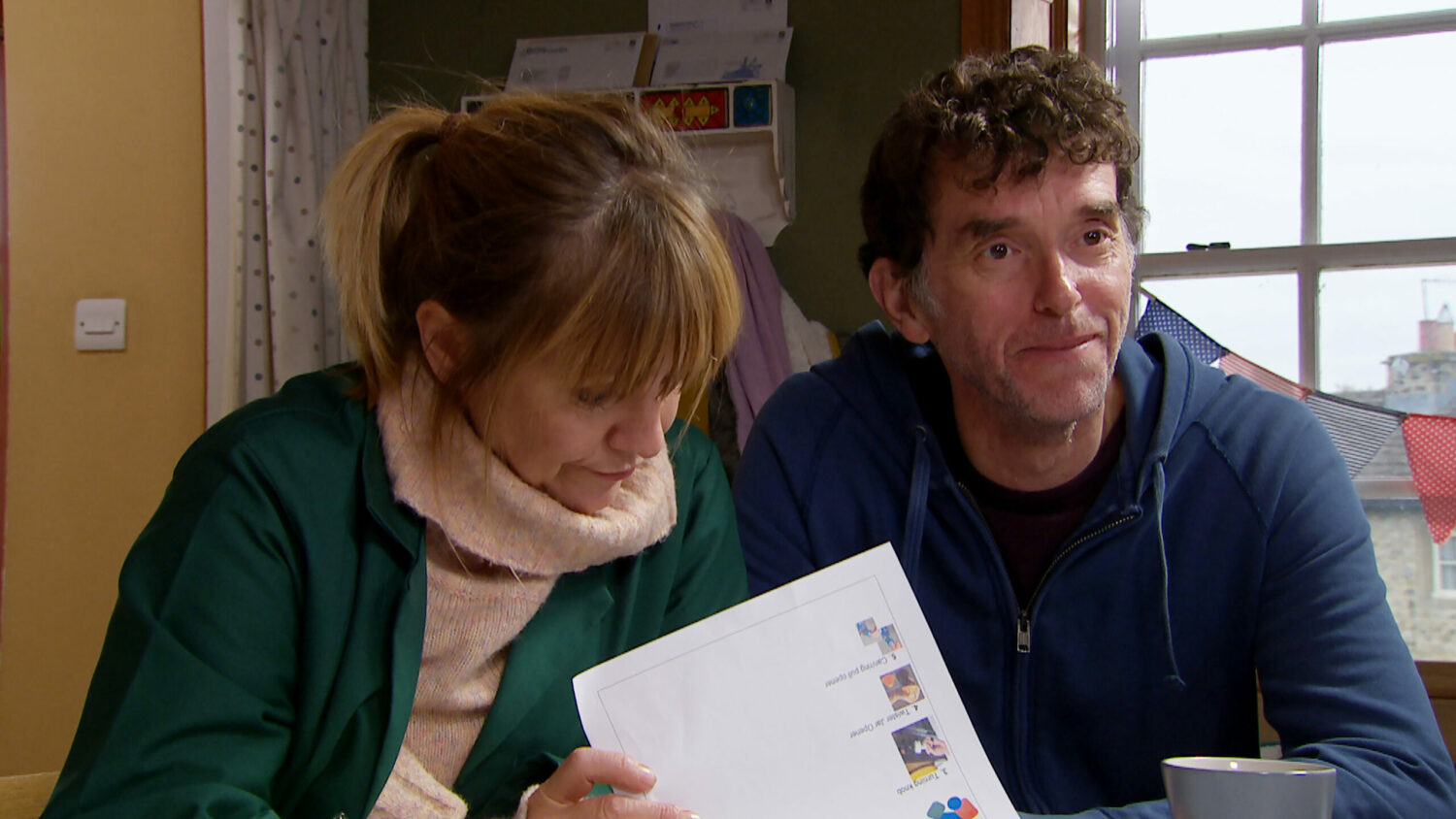Emmerdale's Marlon is smiling as Rhona looks over some papers